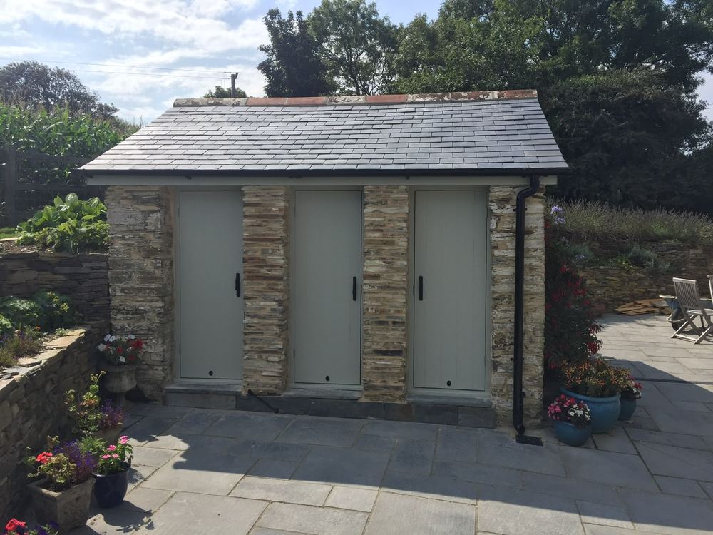 Stone garden room with three pale timber doors